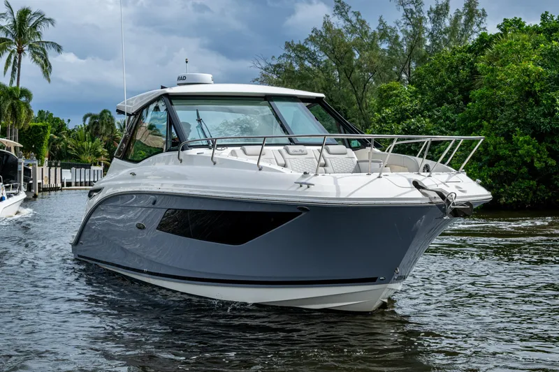  Yacht Photos Pics 2023 Sea Ray Sundancer 320 Outboard cruising on a scenic waterway with lush greenery.