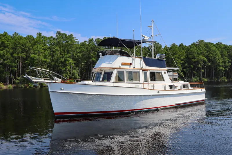 Tallulah Yacht Photos Pics 1989 Grand Banks 42 Classic yacht on calm water, surrounded by lush green trees.