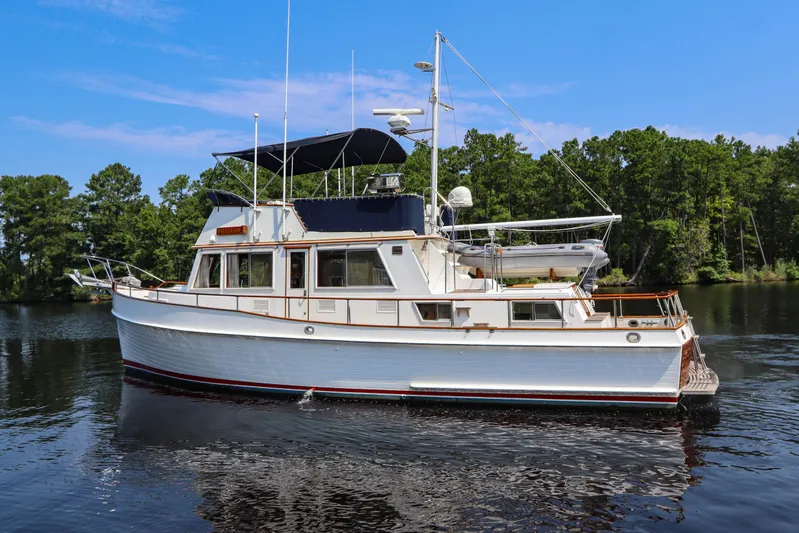Tallulah Yacht Photos Pics 1989 Grand Banks 42 Classic yacht on calm water, surrounded by lush greenery.
