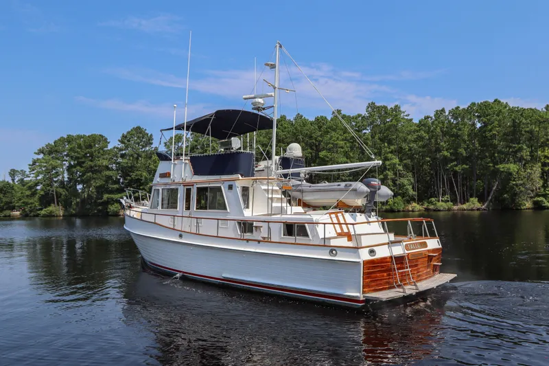 Tallulah Yacht Photos Pics 1989 Grand Banks 42 Classic yacht cruising on a serene lake with lush green trees.
