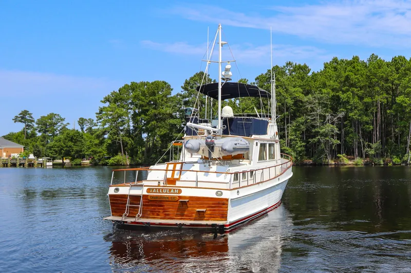 Tallulah Yacht Photos Pics 1989 Grand Banks 42 Classic yacht cruising on a serene lake with lush green trees.