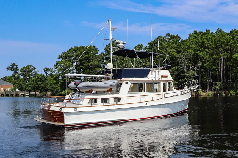 Tallulah Yacht Photos Pics 1989 Grand Banks 42 Classic yacht on a serene lake with lush green trees.