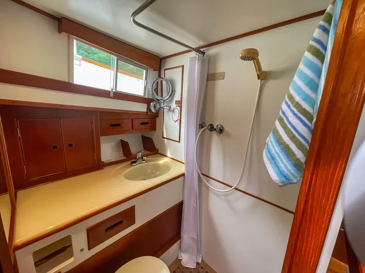Tallulah Yacht Photos Pics 1989 Grand Banks 42 Classic yacht bathroom with shower, sink, and striped towel.