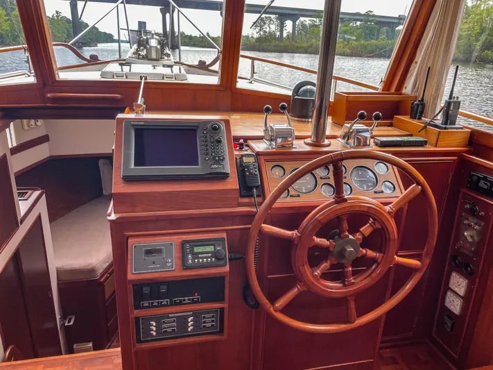 Tallulah Yacht Photos Pics 1989 Grand Banks 42 Classic helm with wooden wheel, navigation instruments, and river view.