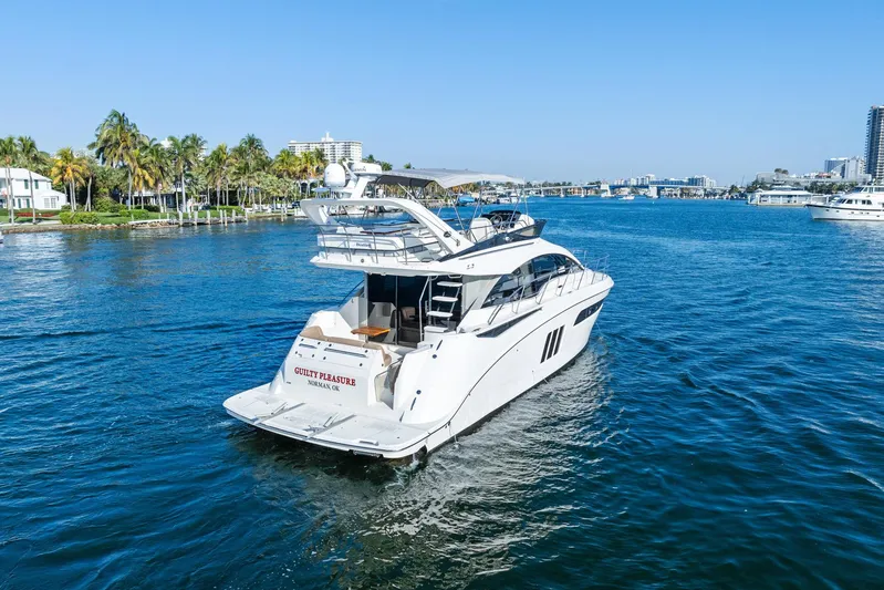 Guilty Pleasure Yacht Photos Pics 2014 Sea Ray 510 Fly yacht cruising on a sunny day near palm-lined shore.