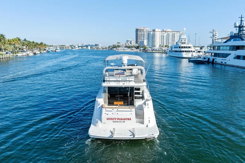 Guilty Pleasure Yacht Photos Pics 2014 Sea Ray 510 Fly yacht cruising in a sunny marina, surrounded by luxury boats.
