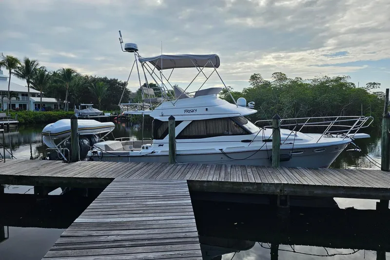 Frisky Yacht Photos Pics 2022 Cuwater C-32-CB boat docked by a wooden pier, surrounded by lush greenery.