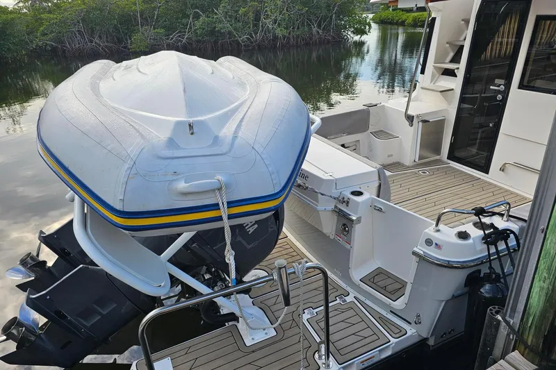 Frisky Yacht Photos Pics 2022 Cuwater C-32-CB boat with inflatable dinghy on deck, docked by lush mangroves.