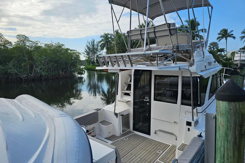 Frisky Yacht Photos Pics 2022 Cuwater C-32-CB boat docked by lush greenery and calm water.