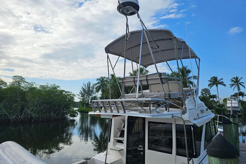 Frisky Yacht Photos Pics 2022 Cuwater C-32-CB boat docked by tropical trees and calm water.