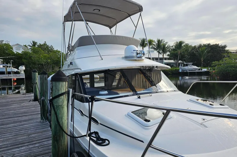 Frisky Yacht Photos Pics 2022 Cuwater C-32-CB boat docked by a wooden pier, surrounded by lush greenery.