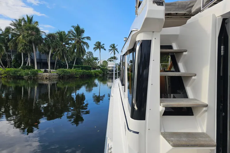 Frisky Yacht Photos Pics 2022 Cuwater C-32-CB boat on a serene river with palm trees and blue sky.