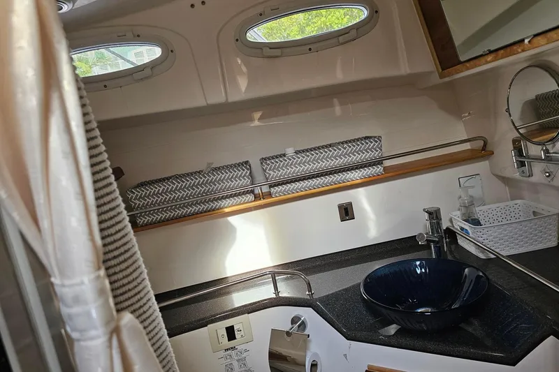 Frisky Yacht Photos Pics Modern boat bathroom with blue glass sink, porthole windows, and sleek countertop. Cuwater C-32-CB 2022 model.