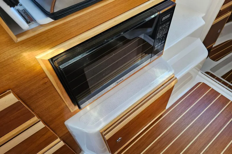 Frisky Yacht Photos Pics Modern boat interior with built-in microwave, wood paneling, and sleek design, Cuwater C-32-CB 2022.