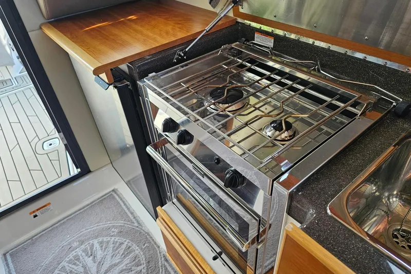 Frisky Yacht Photos Pics Compact kitchen in 2022 Cuwater C-32-CB with stove, sink, and wooden countertop.