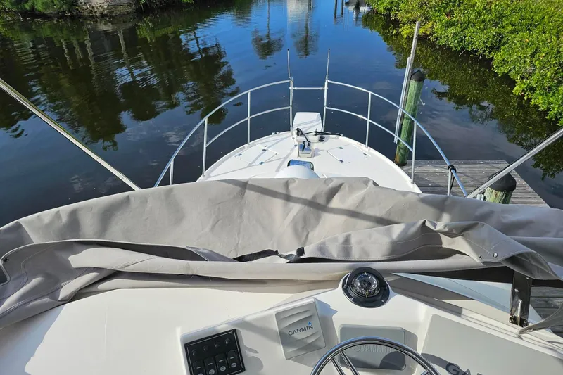 Frisky Yacht Photos Pics 2022 Cuwater C-32-CB boat docked by a serene waterway, featuring a Garmin navigation system.