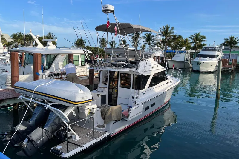 Frisky Yacht Photos Pics 2022 Cuwater C-32-CB boat docked in a marina with fishing rods and inflatable dinghy.