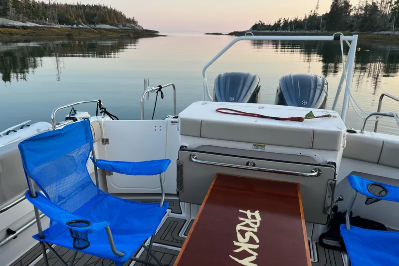Frisky Yacht Photos Pics Boat interior with blue chairs, table labeled "FRISKY," and serene water view. Cuwater C-32-CB, 2022.