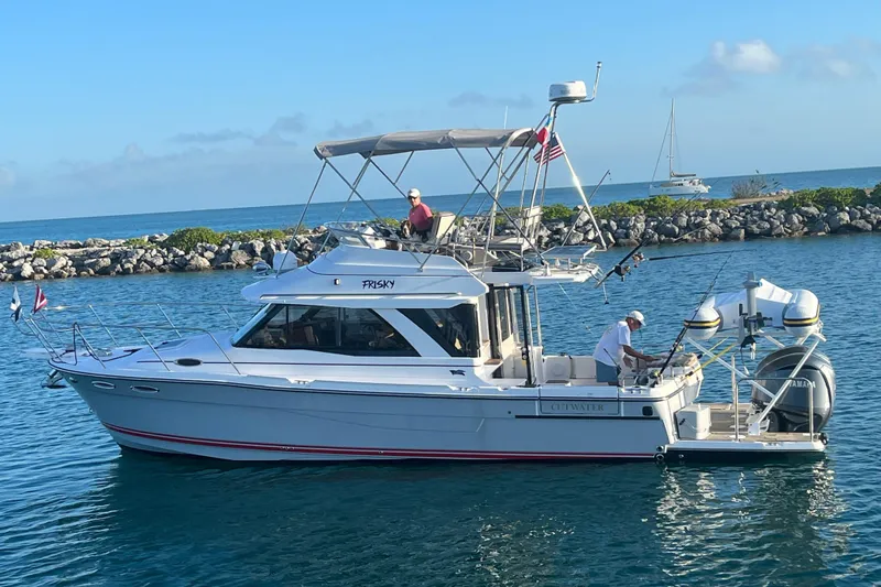 Frisky Yacht Photos Pics 2022 Cuwater C-32-CB boat cruising in clear blue waters near rocky shoreline.