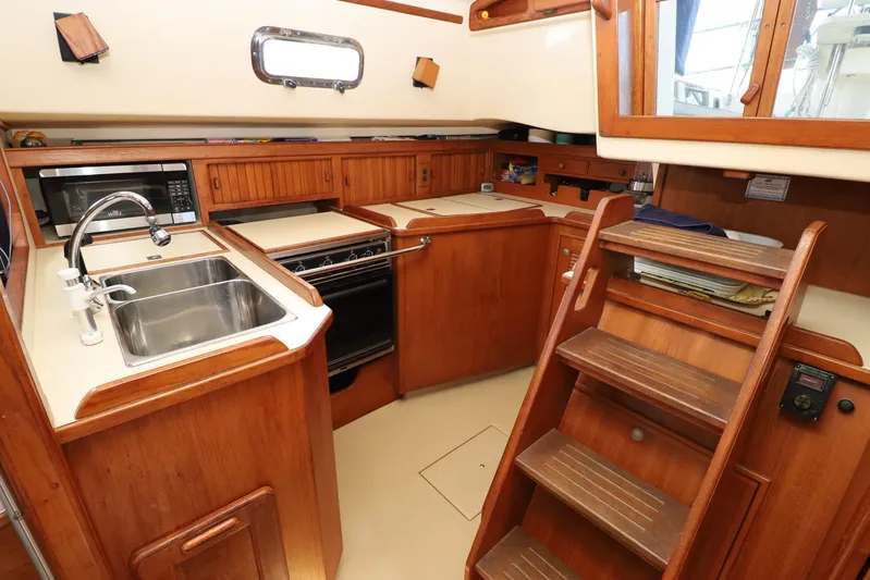 Migaloo Yacht Photos Pics 1996 Island Packet 40 yacht kitchen with wooden cabinetry, sink, stove, and microwave.