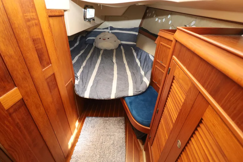 Migaloo Yacht Photos Pics Cozy cabin interior of 1996 Island Packet 40 sailboat with striped bedding and wooden furnishings.
