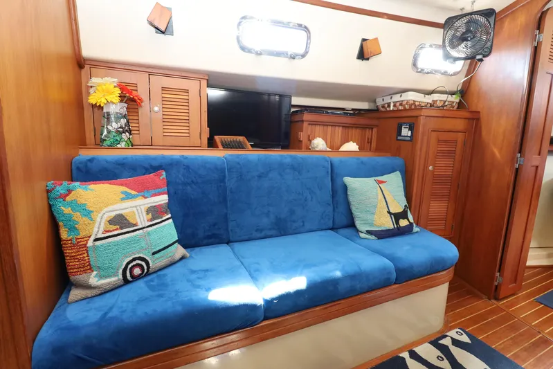 Migaloo Yacht Photos Pics Interior of 1996 Island Packet 40 sailboat with blue sofa and nautical-themed pillows.