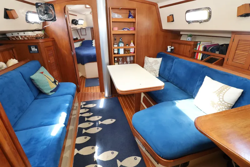 Migaloo Yacht Photos Pics Interior of 1996 Island Packet 40 sailboat with blue seating and wooden accents.
