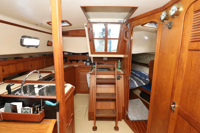 Migaloo Yacht Photos Pics Interior of a 1996 Island Packet 40 sailboat, featuring wood finishes and a compact kitchen.