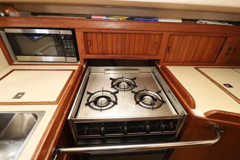 Migaloo Yacht Photos Pics 1996 Island Packet 40 yacht kitchen with stove, microwave, and wooden cabinetry.