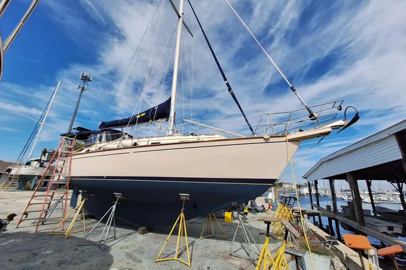 Migaloo Yacht Photos Pics 1996 Island Packet 40 sailboat on dry dock, blue sky background, marina setting.