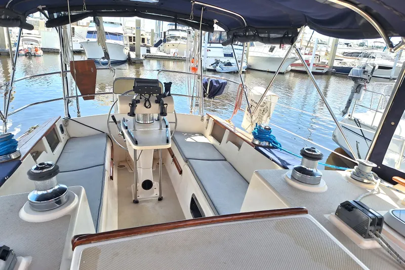 Migaloo Yacht Photos Pics 1996 Island Packet 40 sailboat cockpit with seating, steering wheel, and marina view.