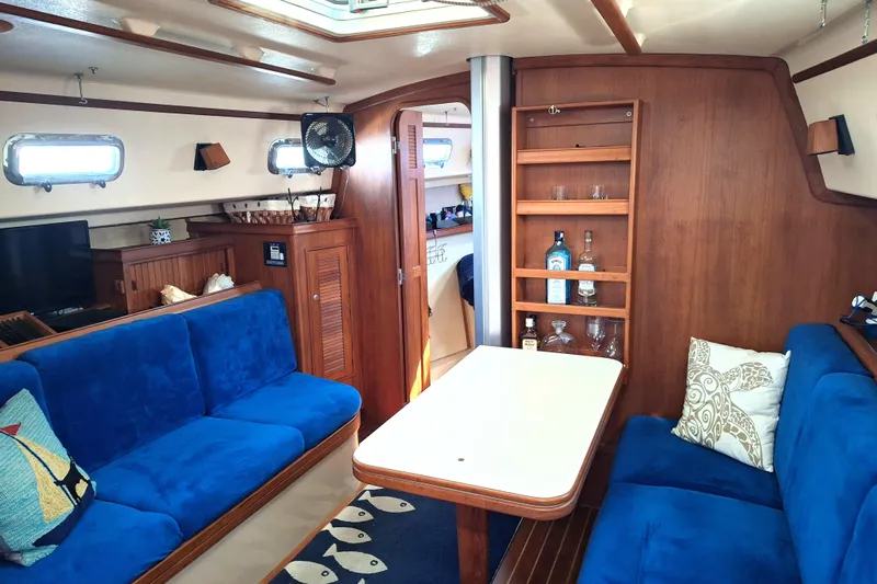 Migaloo Yacht Photos Pics Interior of 1996 Island Packet 40 yacht with blue seating and wooden cabinetry.