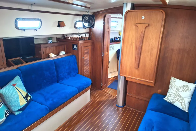 Migaloo Yacht Photos Pics Interior of 1996 Island Packet 40 yacht with blue seating and wooden accents.