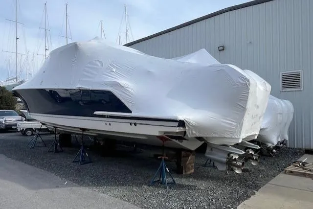  Yacht Photos Pics Covered 2022 Tiara Yachts 43 LS in storage, supported by stands, near a warehouse.