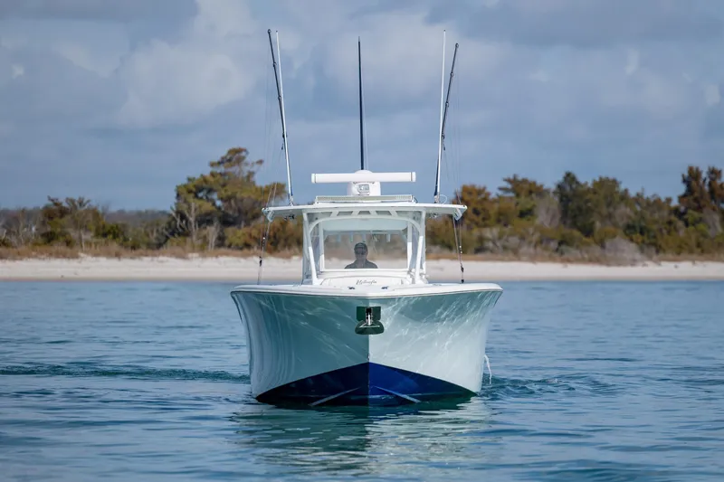  Yacht Photos Pics 2014 Yellowfin 42 Offshore boat cruising on calm water near a sandy shoreline.