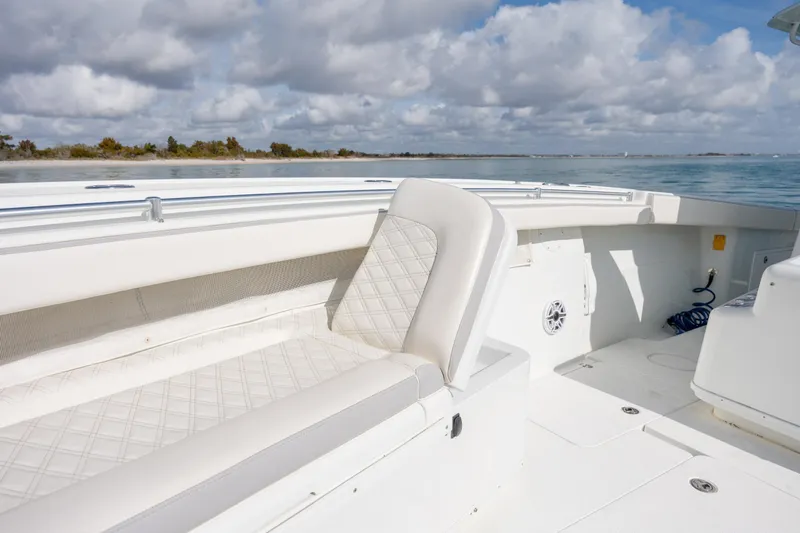  Yacht Photos Pics 2014 Yellowfin 42 Offshore boat interior with white seating, on calm water under cloudy sky.