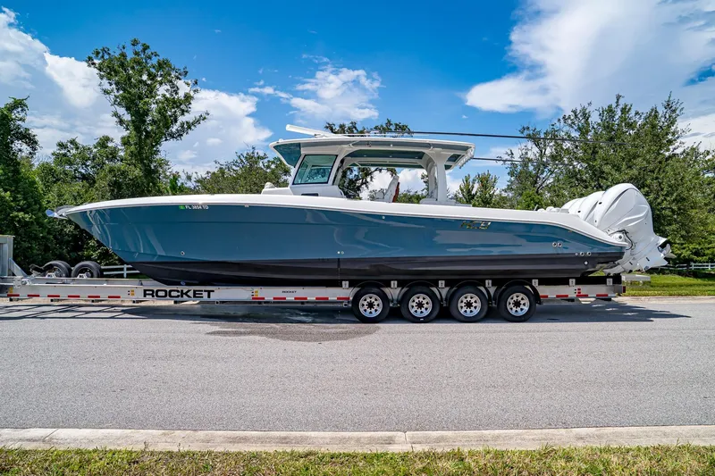  Yacht Photos Pics 2021 HCB Lujo boat on trailer under blue sky, surrounded by trees.