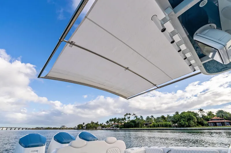 No Name Yacht Photos Pics 2023 HCB 42 Lujo boat with canopy, scenic waterfront view, blue sky, and lush greenery.