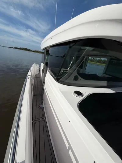  Yacht Photos Pics 2023 Axopar 37 Cross Cabin boat on calm water, showcasing sleek design and modern features.