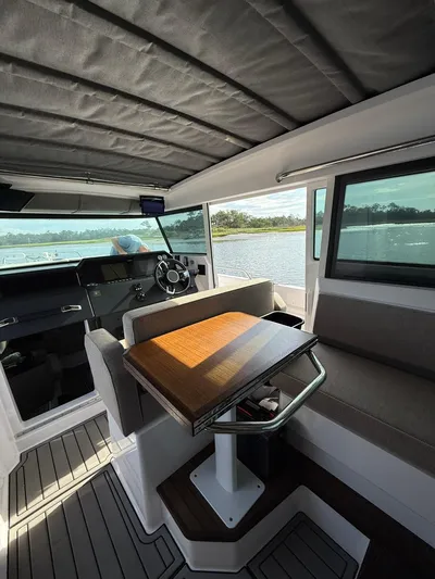  Yacht Photos Pics Interior of 2023 Axopar 37 Cross Cabin boat with seating and table, overlooking water.