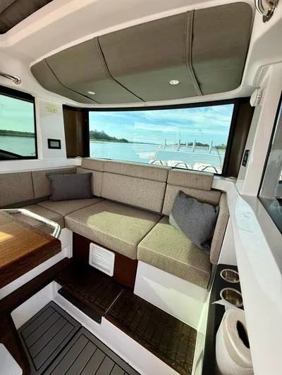  Yacht Photos Pics Interior of 2023 Axopar 37 Cross Cabin with cozy seating and scenic window view.