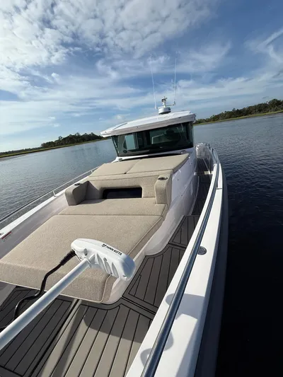  Yacht Photos Pics 2023 Axopar 37 Cross Cabin boat on calm water under a blue sky.