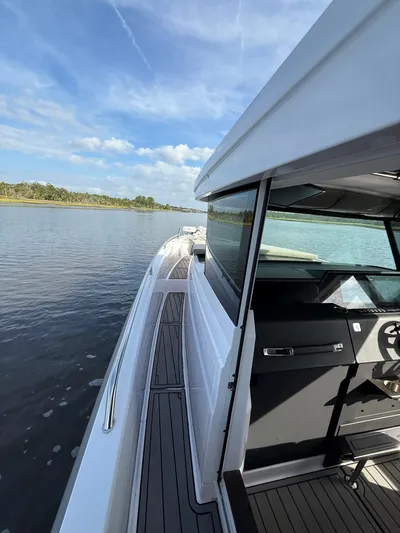  Yacht Photos Pics 2023 Axopar 37 Cross Cabin boat on calm water, showcasing sleek design and modern features.