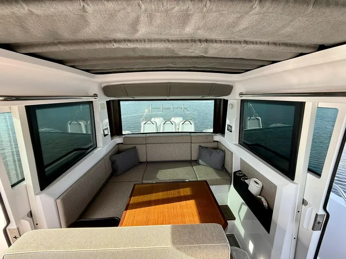  Yacht Photos Pics Interior of 2023 Axopar 37 Cross Cabin with seating and table, overlooking water.