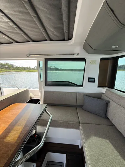  Yacht Photos Pics Interior of 2023 Axopar 37 Cross Cabin with seating and table, overlooking water.