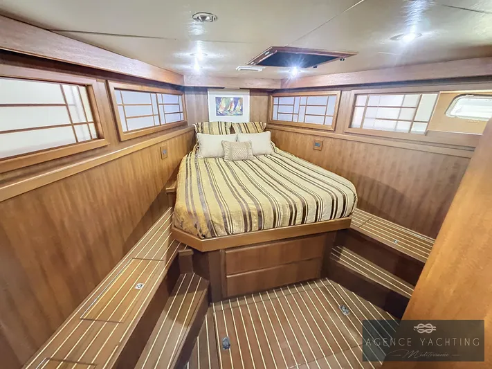  Yacht Photos Pics Luxurious 1987 Hatteras 85 yacht cabin with wood paneling and striped bedding.