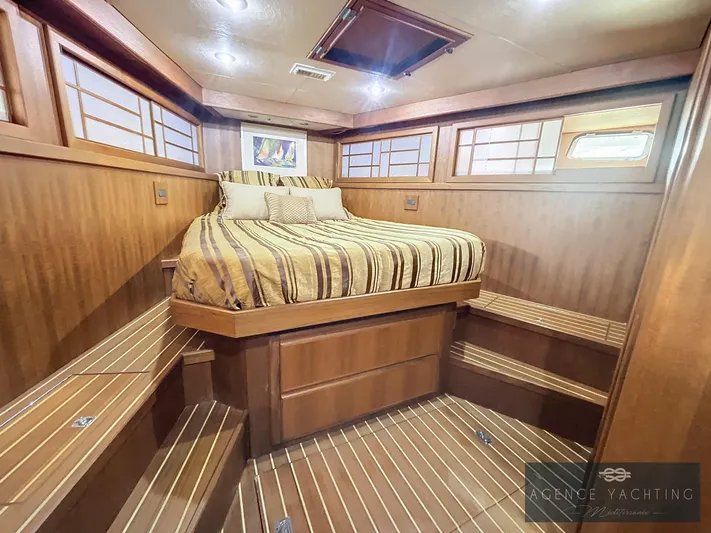  Yacht Photos Pics Luxurious 1987 Hatteras 85 yacht bedroom with wood paneling and striped bedding.