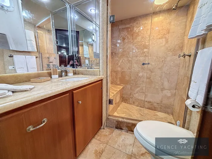  Yacht Photos Pics Luxurious bathroom on 1987 Hatteras 85 yacht with marble shower and wooden cabinetry.