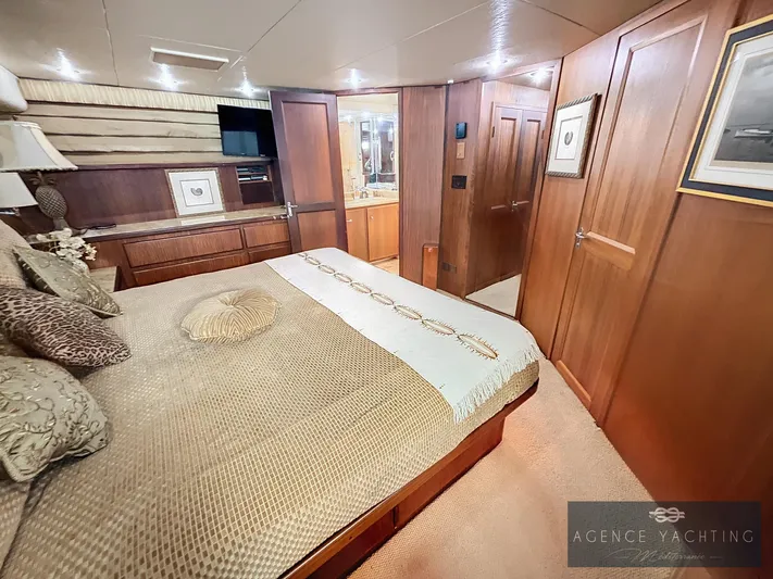  Yacht Photos Pics Luxurious bedroom interior of a 1987 Hatteras 85 yacht with wood paneling and elegant decor.