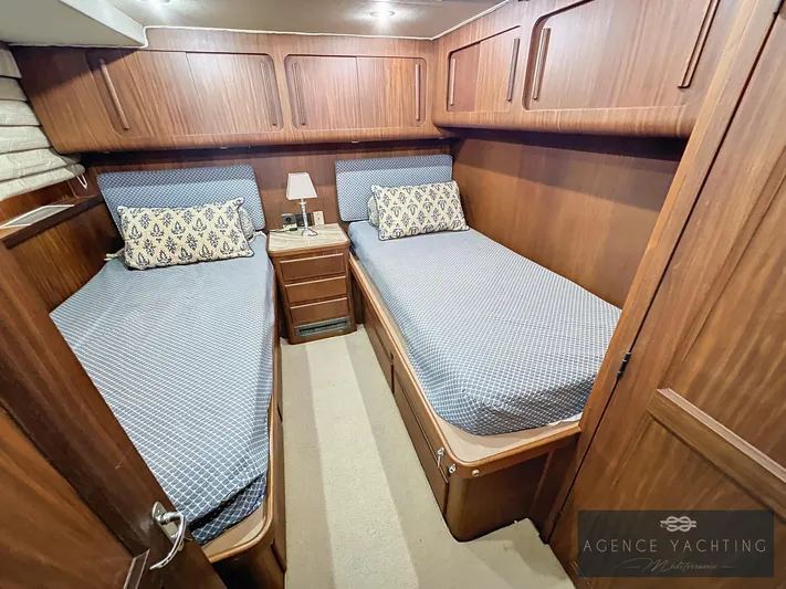  Yacht Photos Pics Twin cabin interior of 1987 Hatteras 85 yacht with wooden finish and blue bedding.